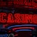 Neon lights display the word 'CASINO' in bright red, standing out against a dark background. The vibrant glow reflects a lively and bustling atmosphere.